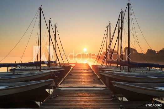 Picture of Tranquil foggy sunrise at a pier with sailing boats
